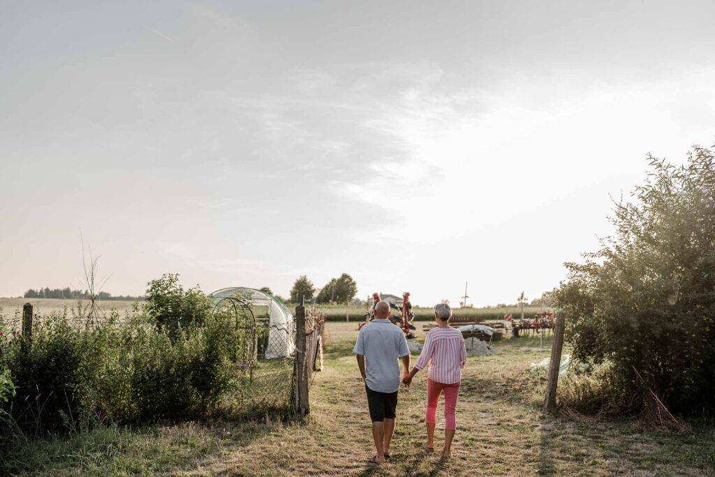 Das Paar Hermann und Martina neben ihrem Permakulturgarten spazierend bei Sonnenuntergang